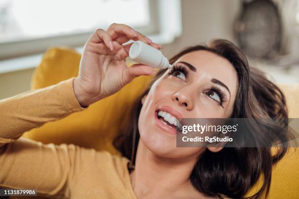 happy woman taking eye drops - colírio imagens e fotografias de stock