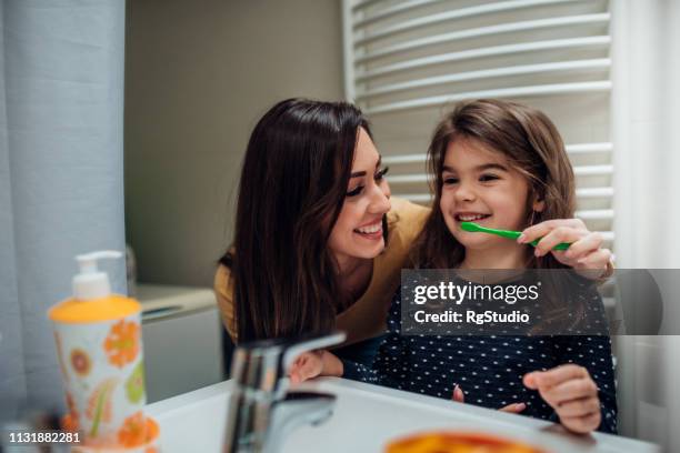 mother and daughter brushing teeth - tooth bonding stock pictures, royalty-free photos & images