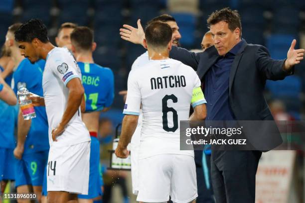 Israel's head coach Andi Herzog speaks with midfielder Bibras Natkho during the Euro 2020 Group G football qualification match between Israel and...