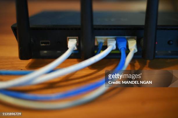 Ethernet cables are seen running from the back of a wireless router in Washington, DC on March 21, 2019.