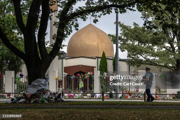 Man works inside Al Noor mosque as an armed police officer patrols the area outside where flowers and tributes have been paid, on March 22, 2019 in...