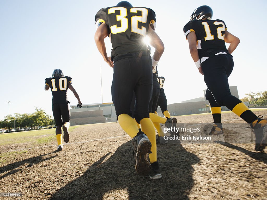 Football players running on football field