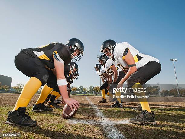 football players crouching on football field - american football team stock pictures, royalty-free photos & images