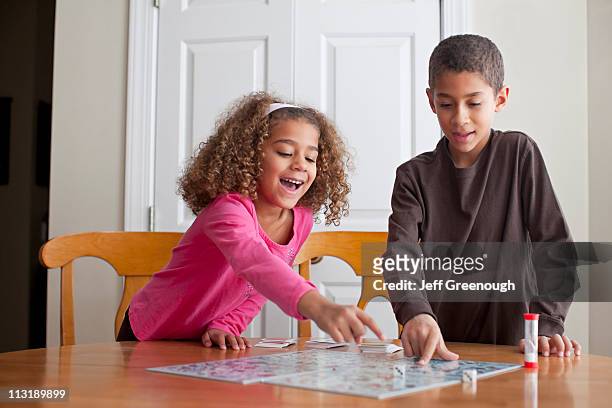 mixed race children playing board game together - game board fotografías e imágenes de stock