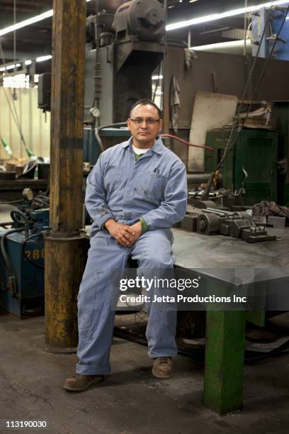 mixed race worker sitting on table in factory - leaning stock pictures, royalty-free photos & images