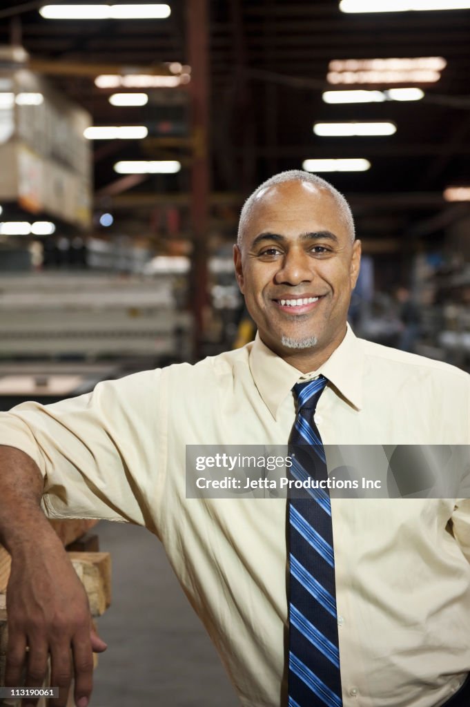 Smiling Black manager standing in factory