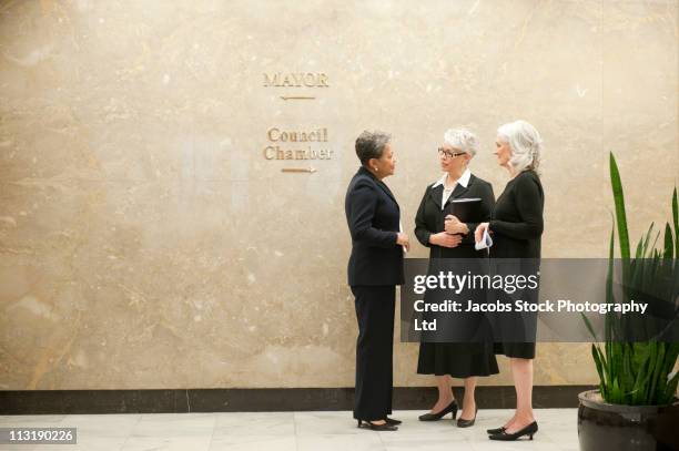businesswomen talking together in office corridor - collaboration government stock pictures, royalty-free photos & images