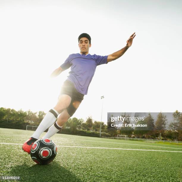 mixed race soccer player kicking soccer ball - dribbling sports stock-fotos und bilder