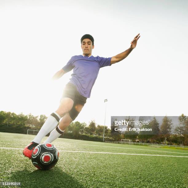 mixed race soccer player kicking soccer ball - dribbling sport fotografías e imágenes de stock