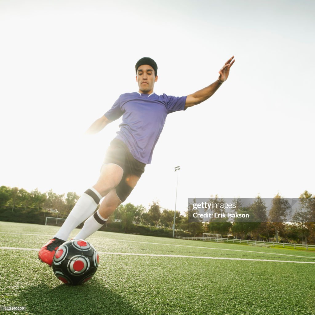 Mixed race soccer player kicking soccer ball