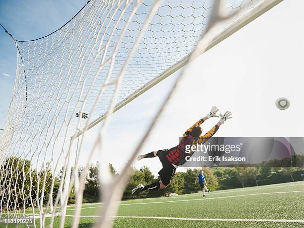 mixed race goalkeeper in mid-air protecting goal - try scoring stock pictures, royalty-free photos & images