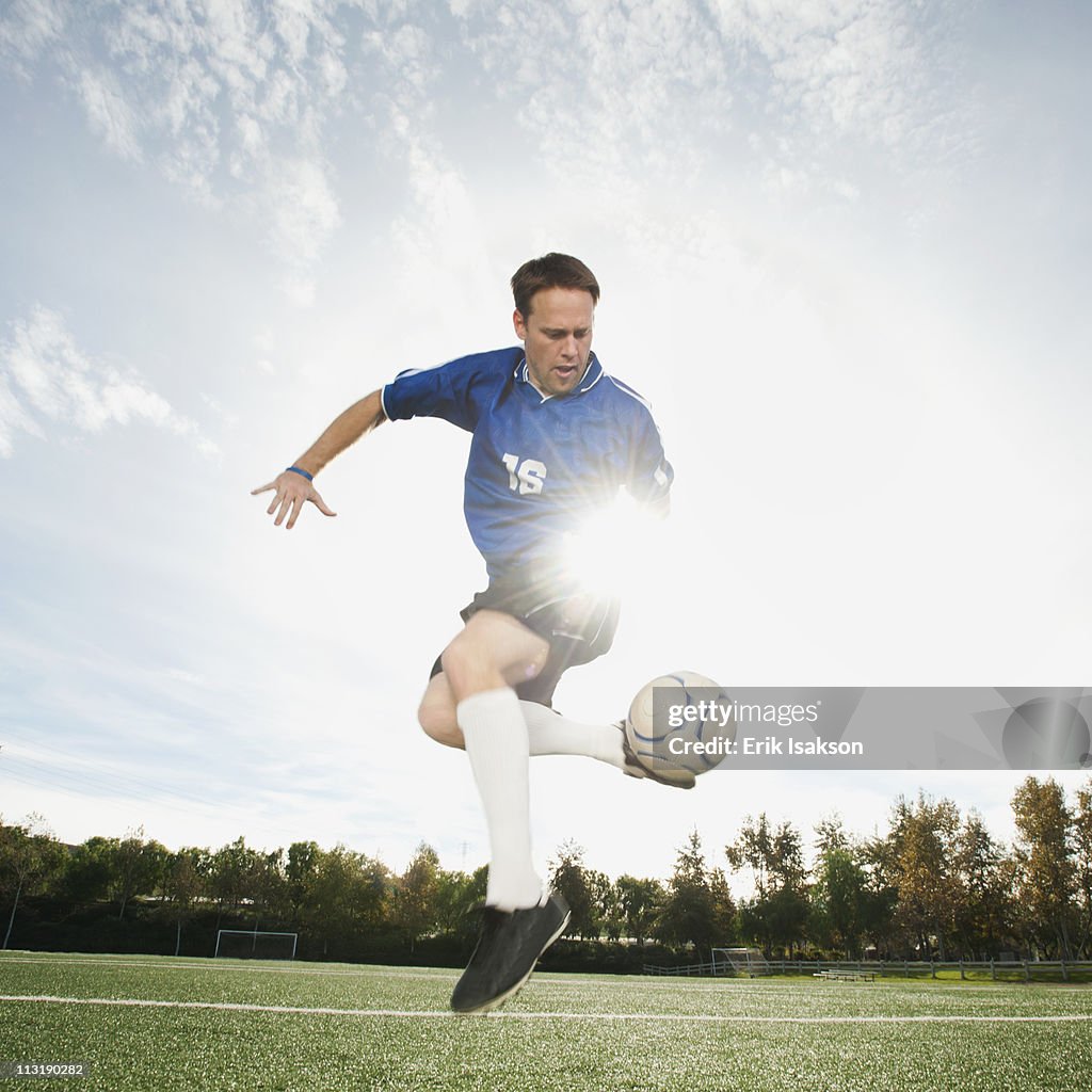 Caucasian soccer player kicking soccer ball