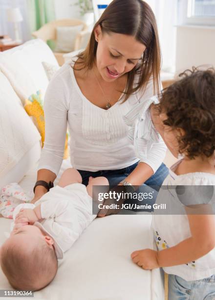 mother changing baby's diaper on sofa - changing diaper photos et images de collection