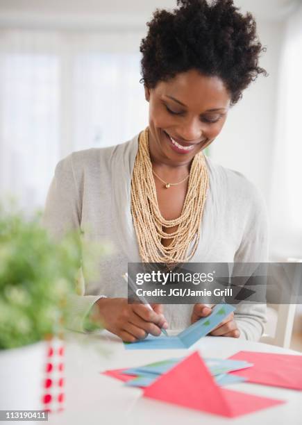 black woman writing on birthday card - thinking of you card stock-fotos und bilder