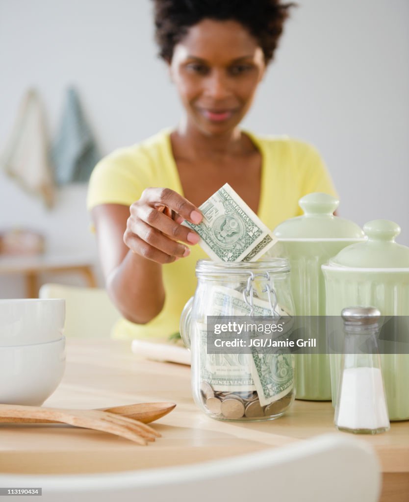 Black woman putting money in jar