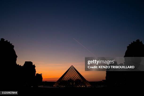 Picture taken on March 21 shows the sunset behind the Louvre Pyramid in Paris. Chinese born US architect Ieoh Ming Pei's pyramid celebrates its 30th...