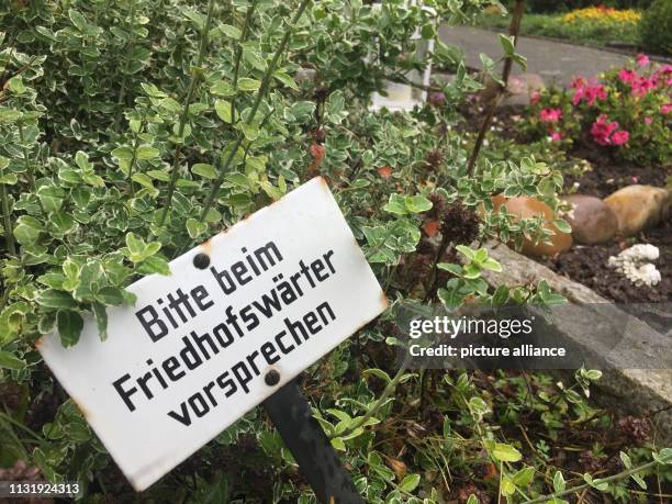 August 2017, North Rhine-Westphalia, Löhne: A sign with the inscription "Bitte beim Friedhofswärter vorsprechen" can be seen on a grave of a...