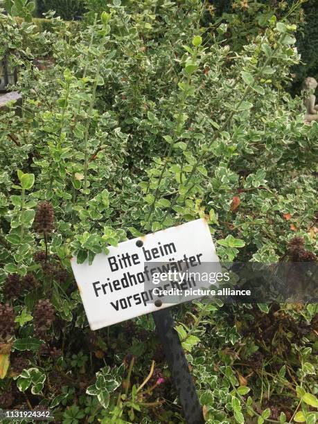 August 2017, North Rhine-Westphalia, Löhne: A sign with the inscription "Bitte beim Friedhofswärter vorsprechen" can be seen on a grave of a...