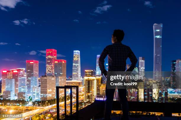 un hombre parado frente a la ciudad moderna - chinese hero fotografías e imágenes de stock