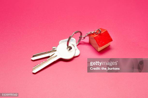 high angle view of keyring with a small house on colored background - house key stock-fotos und bilder