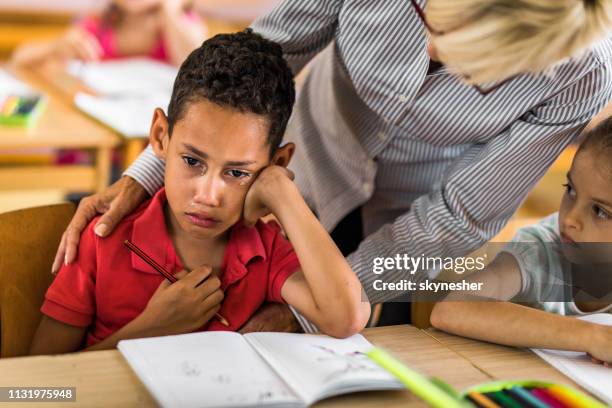 african american elementary student crying on a class while his teacher is consoling him. - bad student stock pictures, royalty-free photos & images