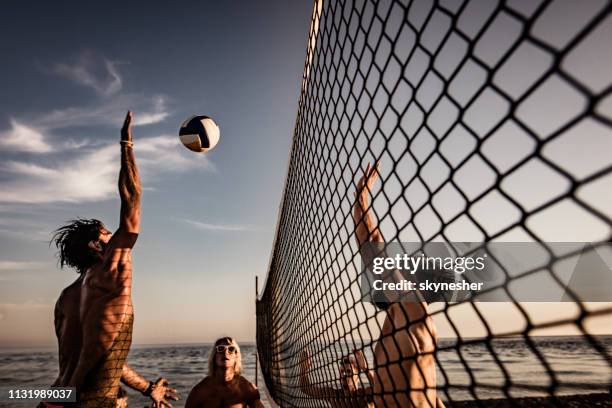 junger mann blockiert seinen freund beim beachvolleyball am sommertag. - volleyball sport stock-fotos und bilder