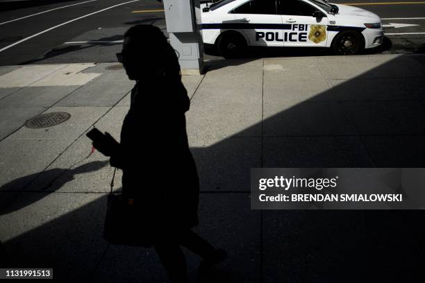 Woman walks past an FBI Police car near one of the office buildings used by independent prosecutor and former FBI director Robert Mueller on March...