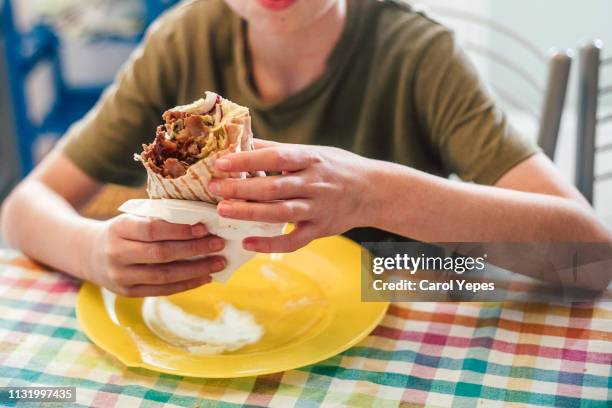 medium section boy eating kebab wrap - kebab stock-fotos und bilder