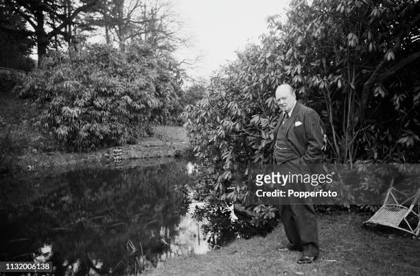 British politician Winston Churchill pictured standing beside a pond in the grounds of Chartwell country house near Westerham in Kent, England in...