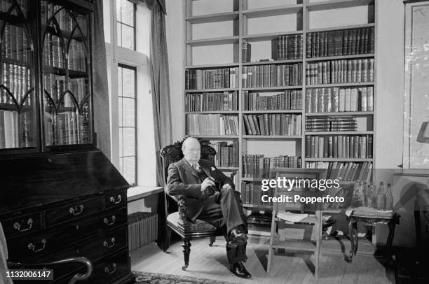 British politician Winston Churchill pictured seated with a cigar in the library of Chartwell country house near Westerham in Kent, England in...