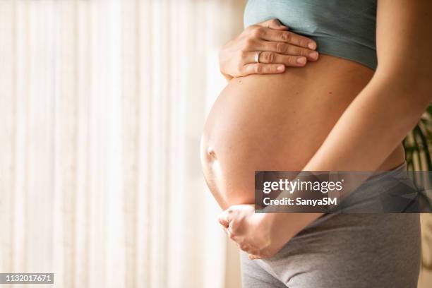 pregnant woman embracing her belly - pregnant belly stock pictures, royalty-free photos & images