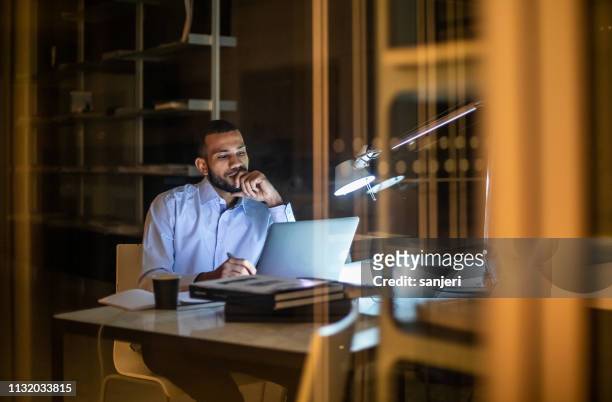 overwerkte zakenman die laat in het bureau werkt - smart numbers office stockfoto's en -beelden