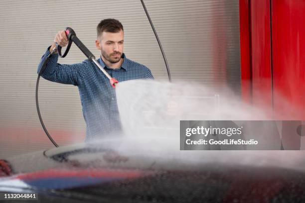 jonge man wassen van zijn auto - industrial hose stockfoto's en -beelden