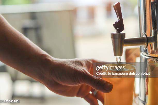 male hand serving water of a water cooler in plastic cup. - water dispenser in office stock pictures, royalty-free photos & images