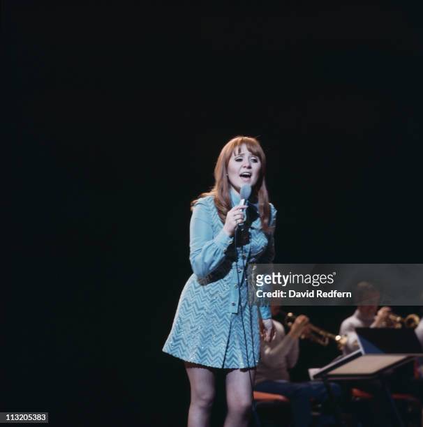 Lulu, British singer, singing into a microphone during a live concert performance, circa 1970.