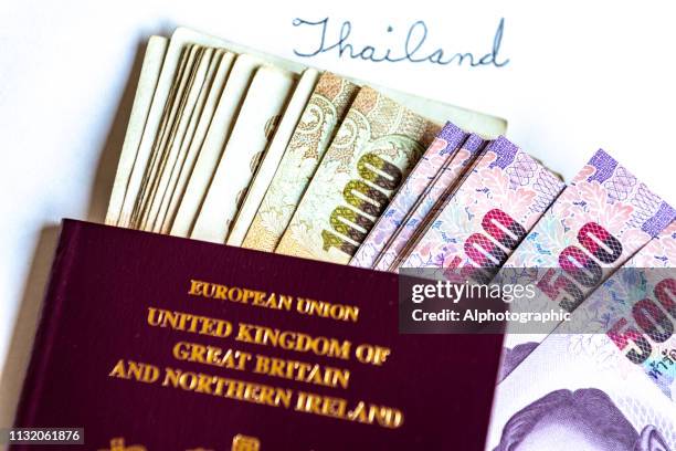 thailand baht notes and uk passports - 1000 baht banknote stock pictures, royalty-free photos & images