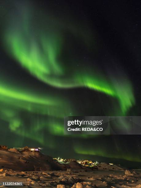 Northern Lights over town and frozen Disko Bay. Town Ilulissat at the shore of Disko Bay in West Greenland. Center for tourism. Administration and...