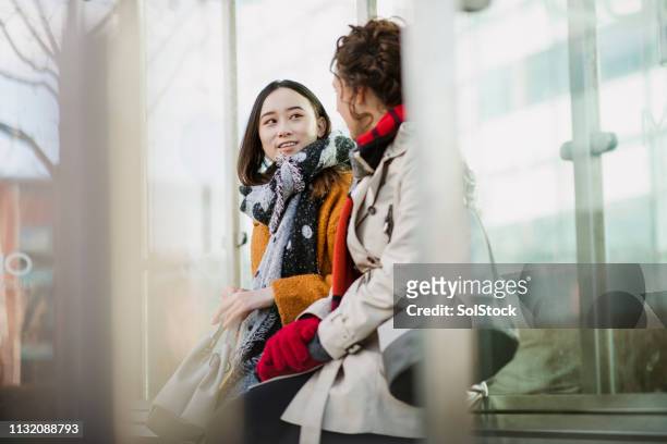 mujeres compañeras esperando el autobús - commuter fotografías e imágenes de stock