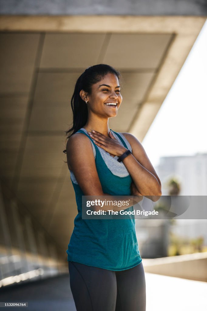 Portrait of happy female runner standing under bridge
