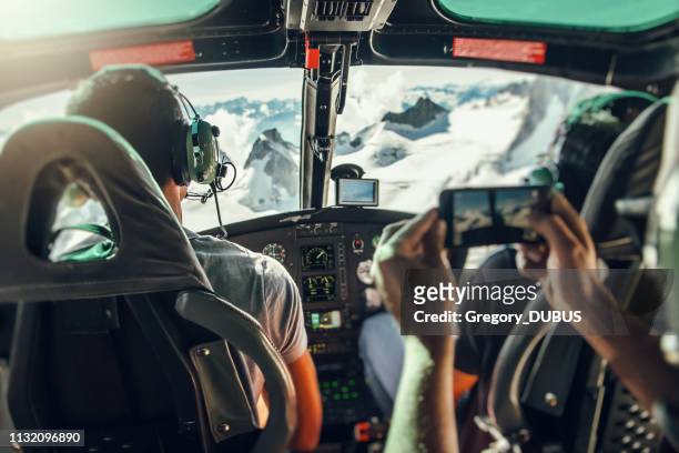 interno dell'abitacolo dell'elicottero con pilota irriconoscibile e turista sfocato che scatta foto del volo sul massiccio del monte bianco - haute savoie foto e immagini stock