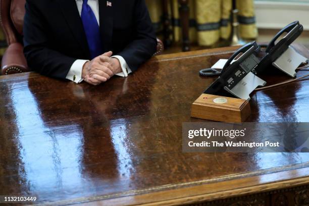 President Donald Trump is reflected on the resolute desk as he speaks during a meeting with Chinese Vice Premier Liu He, right, in the Oval Office of...