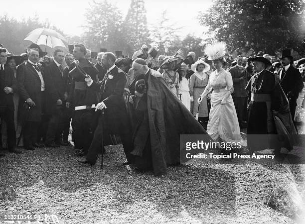 King George V and Queen Mary walking in the grounds of Maynooth College in Maynooth, County Kildare, during a visit to Ireland, July 1911. From left...