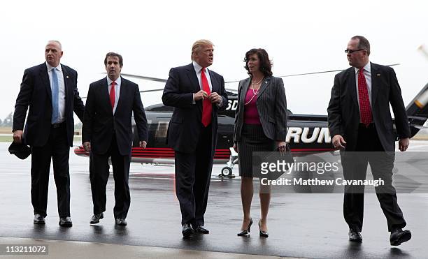 Donald Trump arrives with unidentified aides and security personnel prior to speaking to the media at Pease International Trade Port on April 27,...