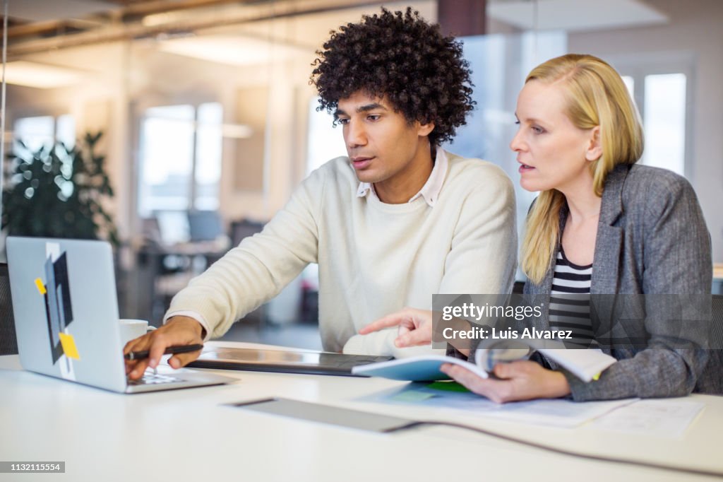 Business colleagues using laptop at office