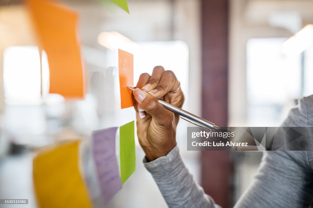 Female writing new ideas on sticky note