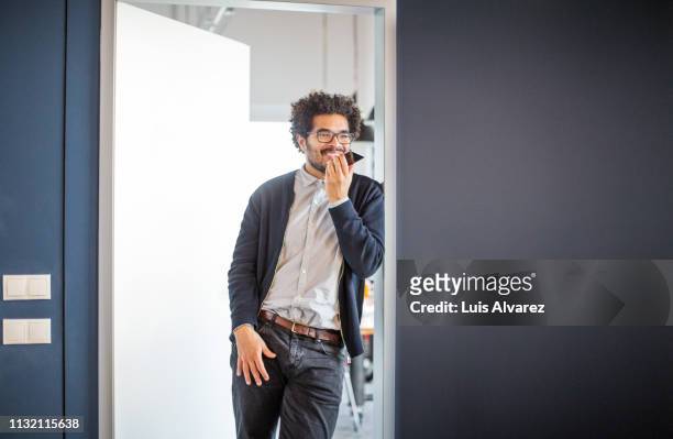young african man talking on his cellphone at office - answering stock-fotos und bilder