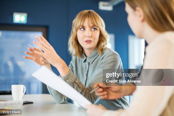 businesswoman sharing ideas with colleague in meeting - information imagens e fotografias de stock