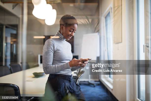 mid adult businesswoman in conference room using cell phone - smartphone office stock-fotos und bilder