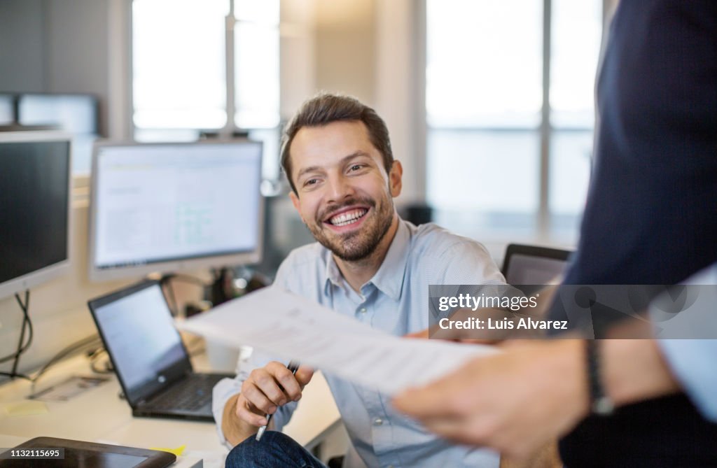 Young businessman sitting at his desk and smiling