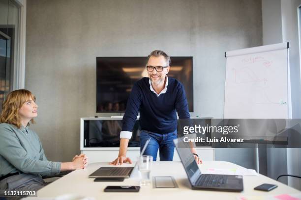 mid adult businessman leading a board room meeting - anführen stock-fotos und bilder